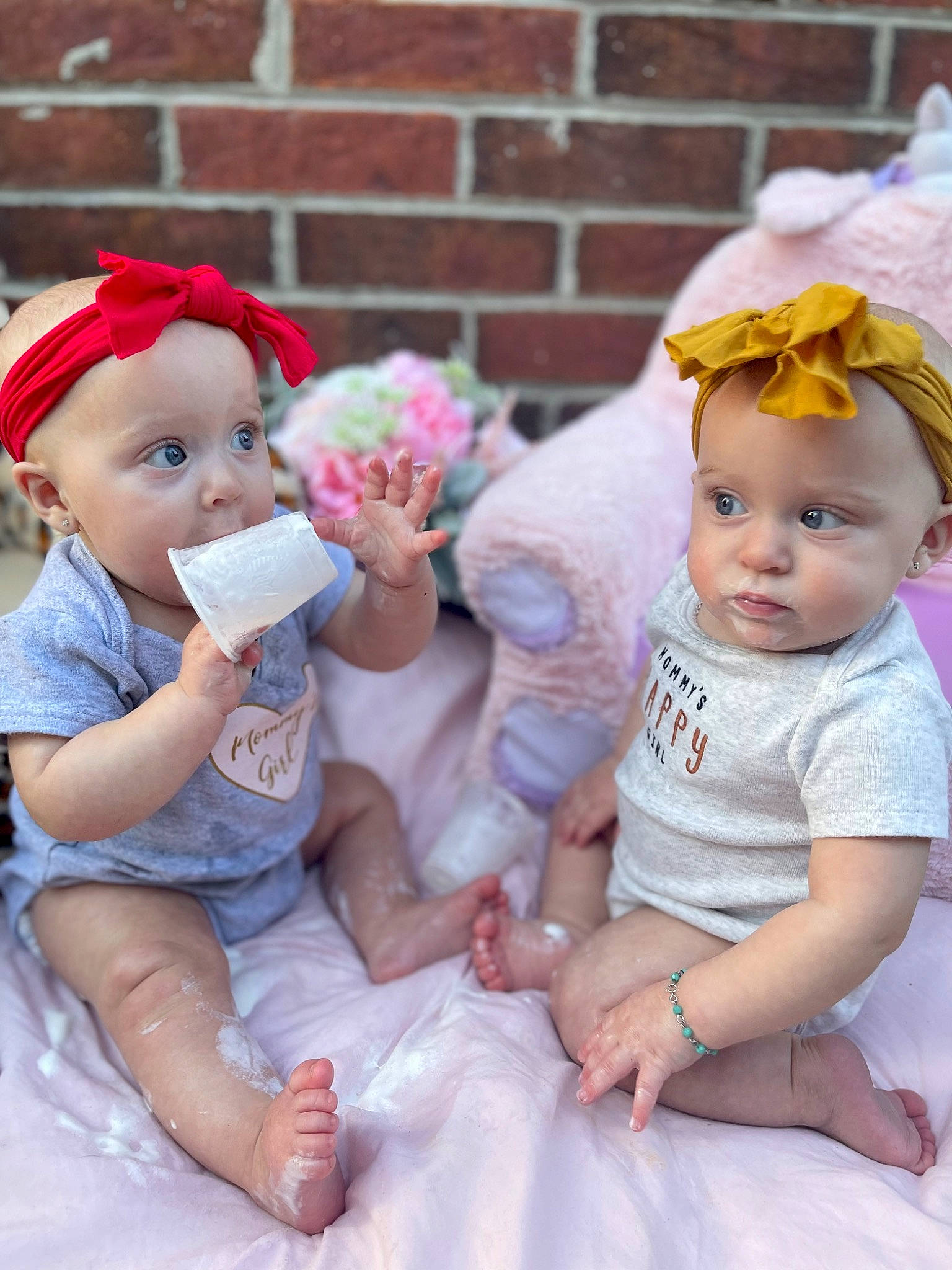 Mia And Mya is registered to the contest to win money with this photo: baby, baby_toddler_clothing, child, event, face, gesture, happy, hat, headgear, headwear, jewellery, person, photograph, pink, plant, purple, sitting, skin, sun_hat, toddler