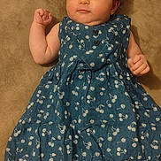 Safa participe au concours pour gagner de l'argent avec cette photo : baby, infant, child, dress, blue_dress, cherry_pattern, lying_down, bed, pillow, barefoot, cute, curious, soft_lighting, indoors, skin, face, hand, foot, person, portrait