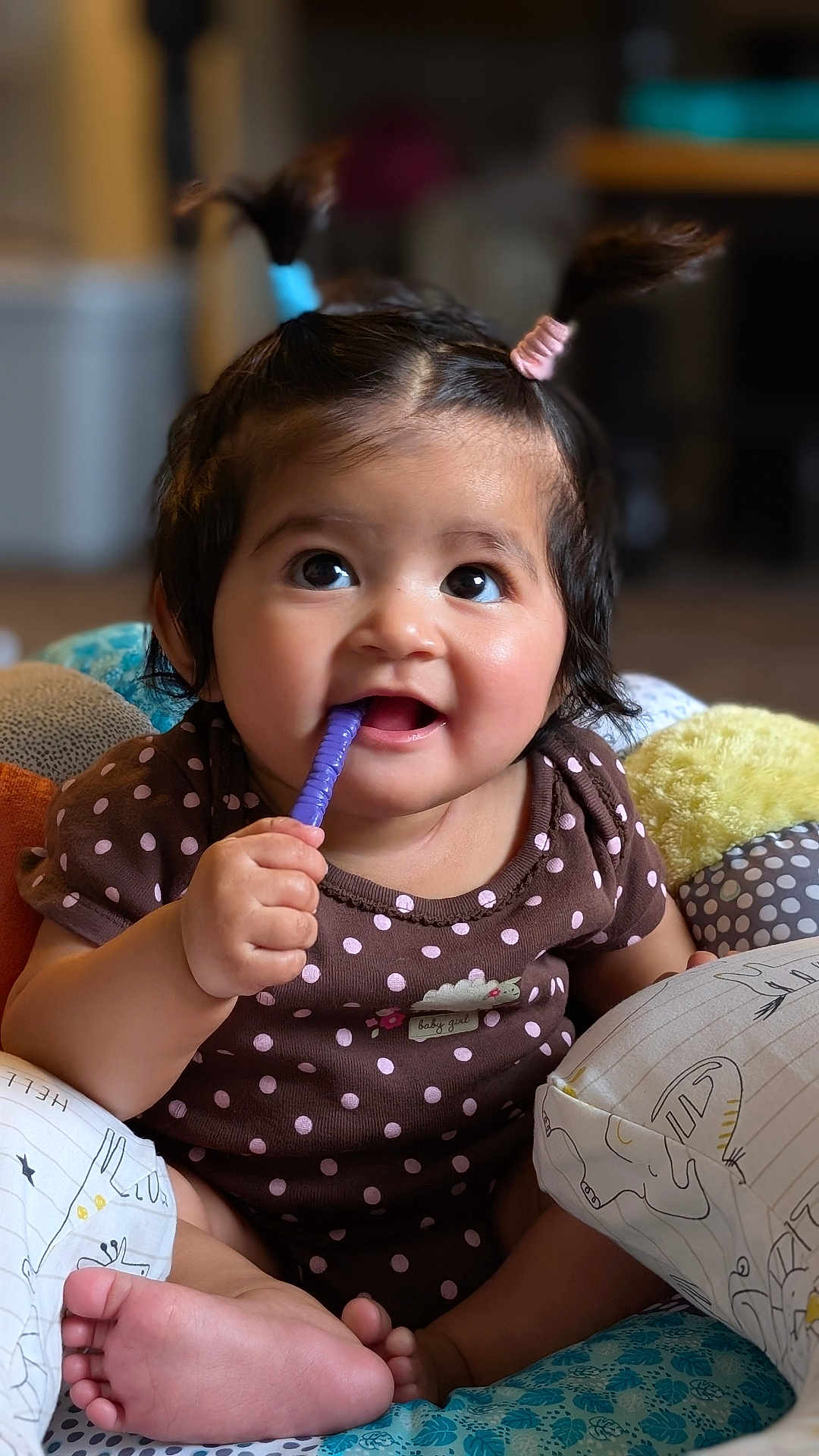 Sparsha is registered to the contest to win money with this photo: baby, brown_clothing, child, cushion, cute, face, foot, hand, happy, indoors, infant, pigtails, playful, polka_dot, portrait, purple, sitting, smiling, toddler, toy