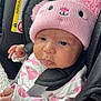 baby, child, infant, pink_hat, knit_hat, car_seat, seat_belt, heart_pattern, white_clothing, black_car_seat, blanket, cute, face, portrait, indoors, close_up, infant_clothing, baby_girl, soft_light, calm_expression