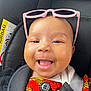Ilyana participe au concours pour gagner de l'argent avec cette photo : baby, smile, sunglasses, car_seat, button, clothing, face, infant, happy, cute, child, seatbelt, patterned_clothing, black_background, headwear, portrait, closeup, skin, eyes, mouth