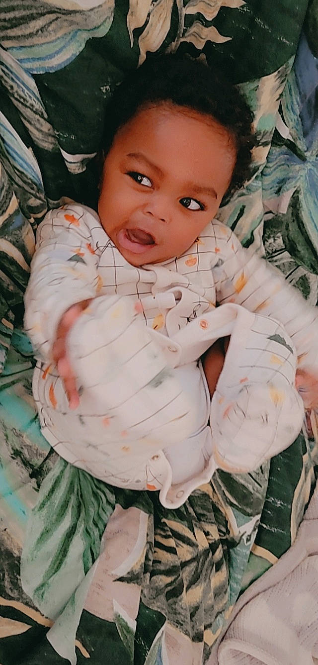 Saleem is registered to the contest to win money with this photo: baby, baby_toddler_clothing, cheek, child, comfort, eye, gesture, grass, happy, head, iris, linens, lip, pattern, peach, person, sitting, skin, sleeve, textile