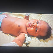 Brandon joined the competition — help win amazing prizes! baby, infant, diaper, mittens, blanket, lying_down, face, skin, cute, child, portrait, young, person, expression, indoors, soft_light, head, curly_hair, resting, newborn