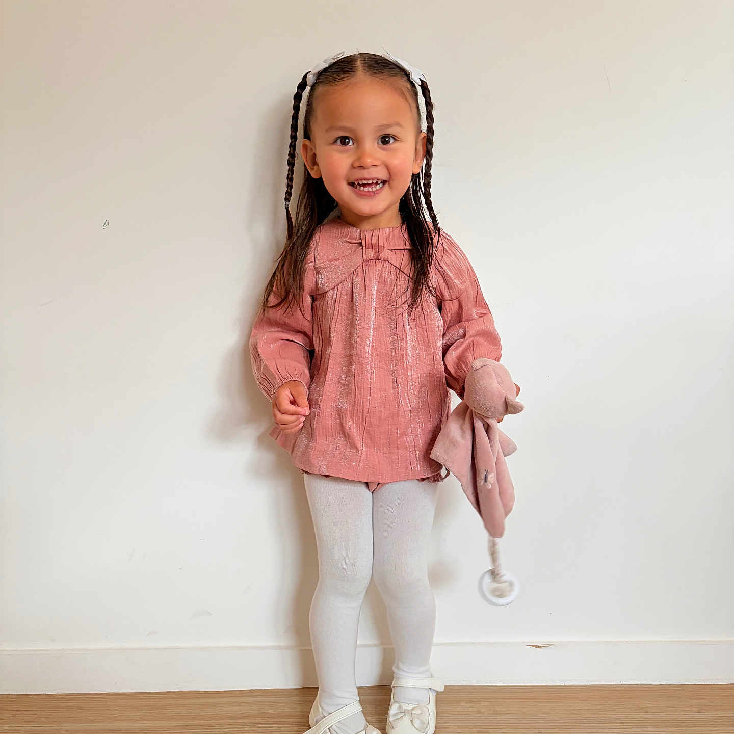 Layana a rejoint le concours — aidez-le/la à gagner de superbes lots ! bow, braided_hair, child, cute, fashion, floor, full_body, girl, happy, headband, indoor, pink_top, plush_toy, portrait, smiling, standing, white_shoes, white_tights, white_wall, young_child