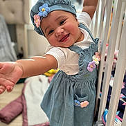 Marcela joined the competition — help win amazing prizes! baby, child, smiling, blue_dress, flower, hat, crib, blanket, indoor, happy, person, cute, toddler, playful, clothing, furniture, soft_toys, floor, home, portrait
