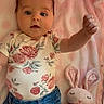 baby, infant, child, floral_clothing, denim_jeans, pink_blanket, soft_toy, plush_bunny, raised_arm, cute, indoors, portrait, laying_down, happy, face, head, hand, fabric, comfort, childhood