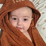 Isaé participe au concours pour gagner de l'argent avec cette photo : baby, towel, brown_towel, face, child, bed, blanket, cute, infant, portrait, eyes, skin, head, expression, indoors, lying_down, fabric, soft_texture, wrapped, cozy