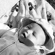 Maël a rejoint le concours — aidez-le/la à gagner de superbes lots ! baby, child, hoodie, blanket, mickey_mouse, outdoor, grass, smile, face, person, infant, clothing, playful, sunlight, shadow, happy, cute, lying_down, portrait, black_and_white