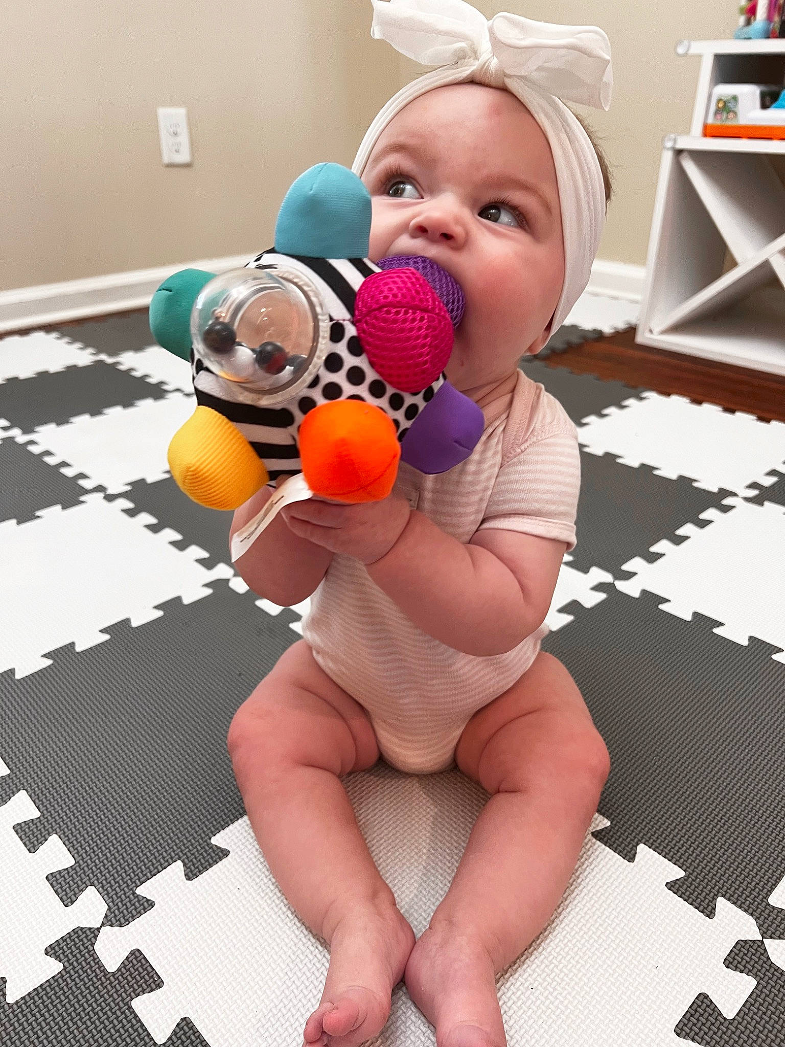 Clara is registered to the contest to win money with this photo: baby, baby_toys, child, comfort, facial_expression, flooring, foot, fun, happy, headwear, human_leg, leisure, person, play, product, room, sitting, skin, stuffed_toy, textile