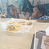 child, toddler, breakfast, food, sandwich, tater_tots, scrambled_eggs, table, restaurant, fast_food, stroller, chair, braided_hair, eating, meal, indoor, person, cute, dining, happy