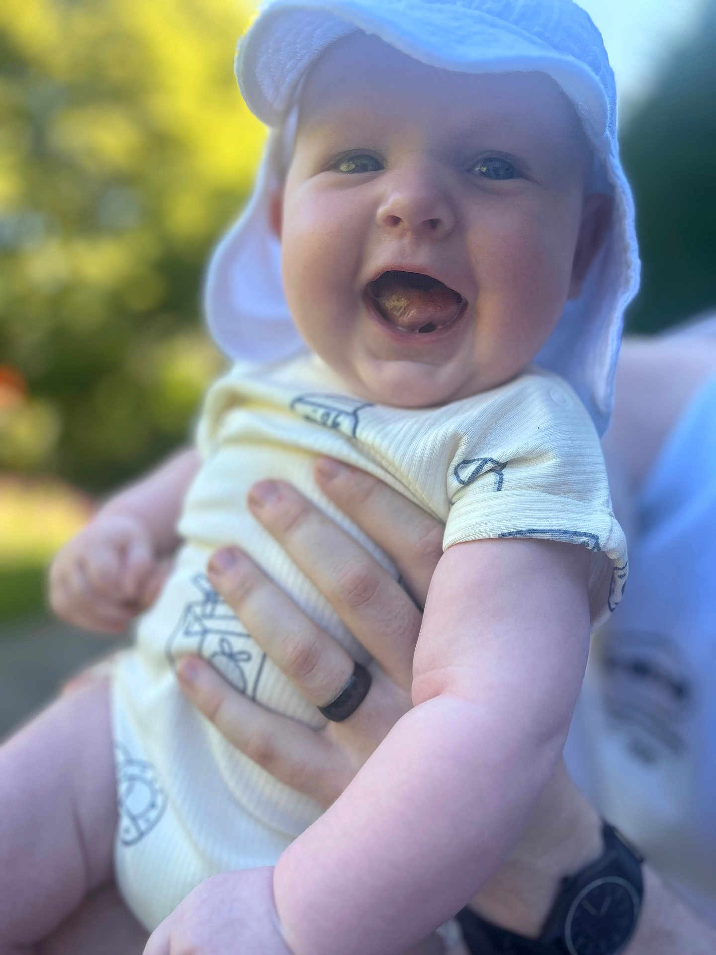 Kraven joined the competition — help win amazing prizes! adult, baby, blurred_background, child, cute, face, greenery, hand, happy, hat, holding, nature, onesie, outdoor, person, portrait, skin, smiling, sunlight, tongue