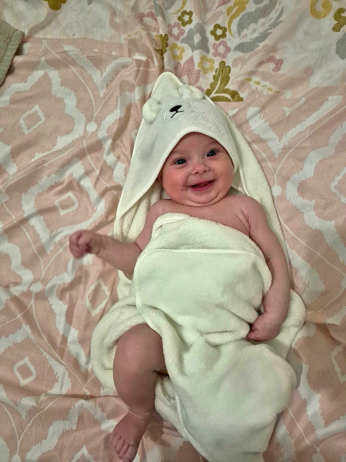 Riana-Maria participe au concours pour gagner de l'argent avec cette photo : baby, towel, smiling, infant, blanket, bed, cute, face, child, happy, hood, soft, lying_down, skin, person, pattern, fabric, comfort, indoors, young