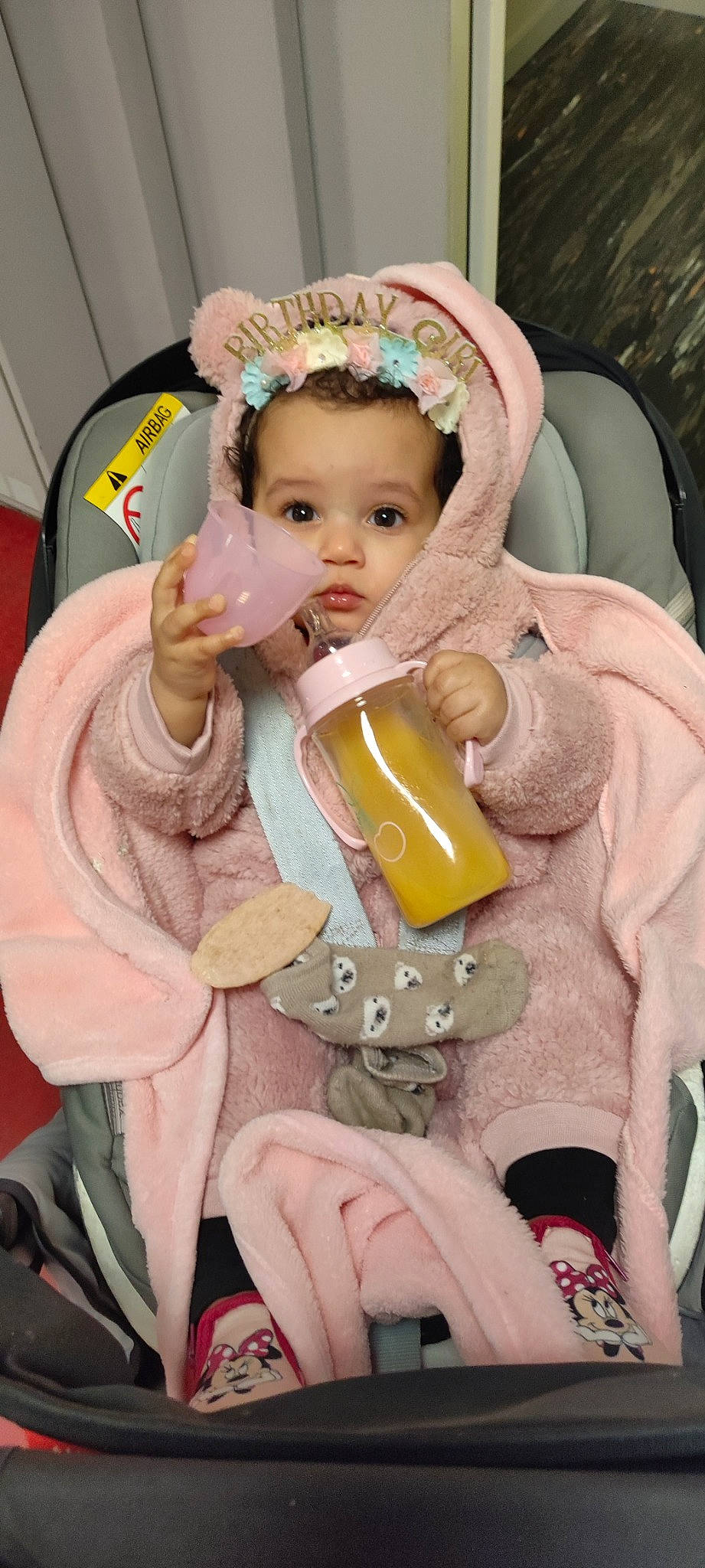 Fatoumata participe au concours pour gagner de l'argent avec cette photo : baby, baby_products, baby_toddler_clothing, bottle, cheek, child, costume, doll, drinkware, eyelash, fashion_accessory, fun, head, person, pink, plastic_bottle, sitting, skin, stuffed_toy, toddler
