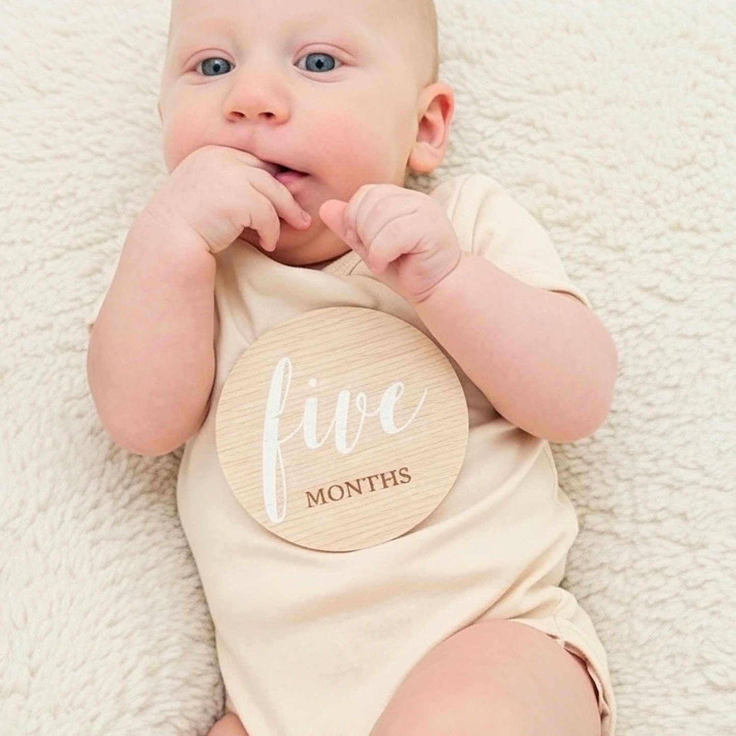 Owen joined the competition — help win amazing prizes! baby, infant, child, onesie, blanket, milestone, wooden_plaque, hand, face, blue_eyes, skin, lying_down, cute, soft_texture, indoors, portrait, fingers, young, expression, resting