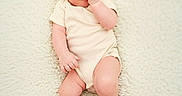 Owen is registered to the contest to win money with this photo: baby, blue_eyes, child, cream_color, curious_expression, cute, fluffy_rug, foot, hand_in_mouth, head, indoors, infant, lying_down, newborn, onesie, person, portrait, resting, skin, soft_texture