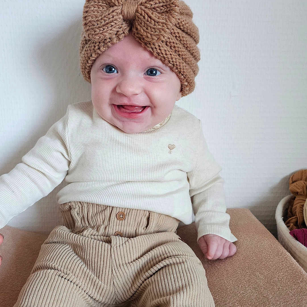 Elaia participe au concours pour gagner de l'argent avec cette photo : baby, blue_eyes, bow, child, corduroy_pants, cozy, cream_clothing, cute, face, happy, headband, indoors, infant, knitted, long_sleeves, neutral_colors, portrait, sitting, smiling, texture