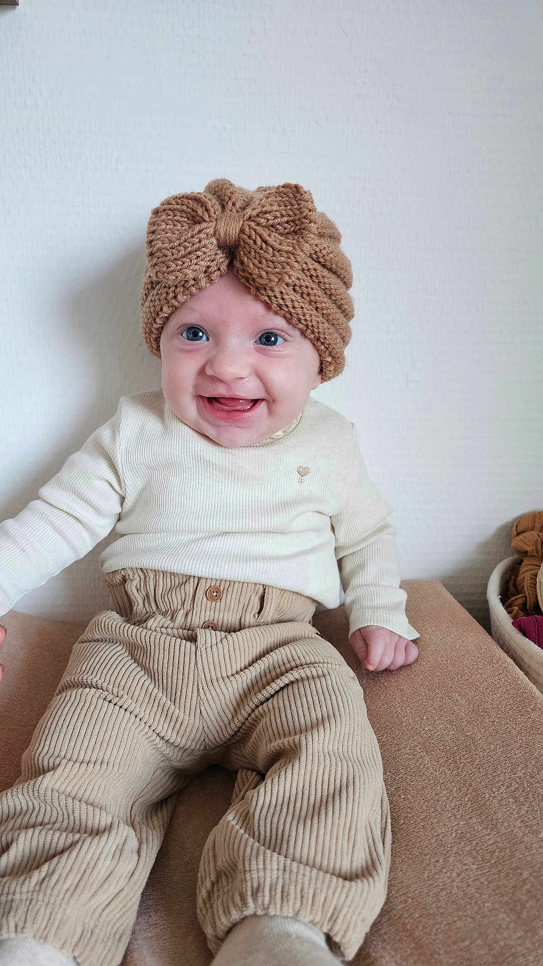 Elaia participe au concours pour gagner de l'argent avec cette photo : baby, child, smiling, headband, knitted, bow, cream_clothing, corduroy_pants, sitting, indoors, happy, cute, portrait, face, blue_eyes, long_sleeves, infant, cozy, neutral_colors, texture