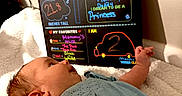 Marley is registered to the contest to win money with this photo: baby, blanket, blue_dress, child, colorful_text, cute, face, handwritten, head, indoors, infant, lying_down, milestone, milestone_board, newborn, person, small, soft_texture, two_months, wall