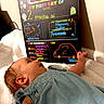 Marley is registered to the contest to win money with this photo: baby, infant, blue_dress, blanket, milestone_board, colorful_text, handwritten, wall, soft_texture, lying_down, cute, small, child, indoors, person, head, face, newborn, two_months, milestone