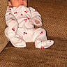 Marley joined the competition — help win amazing prizes! baby, child, onesie, cherry_print, couch, fabric, textured, seated, indoor, person, infant, looking_away, footwear, cozy, home, furniture, cute, small, curious, plush_toy
