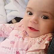 Aubree Addington joined the competition — help win amazing prizes! baby, infant, child, face, eyes, smile, pink_clothing, blanket, soft_texture, close_up, portrait, cute, happy, lying_down, indoors, warm_lighting, skin, head, young, person