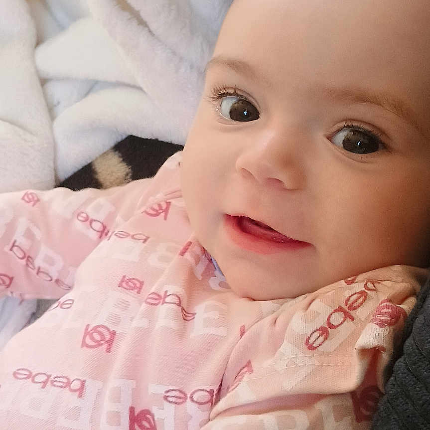 Aubree Addington joined the competition — help win amazing prizes! baby, blanket, child, close_up, cute, eyes, face, happy, head, indoors, infant, lying_down, person, pink_clothing, portrait, skin, smile, soft_texture, warm_lighting, young