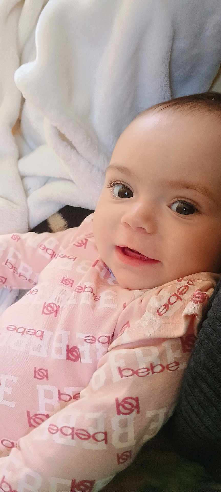 Aubree Addington joined the competition — help win amazing prizes! baby, infant, child, face, eyes, smile, pink_clothing, blanket, soft_texture, close_up, portrait, cute, happy, lying_down, indoors, warm_lighting, skin, head, young, person