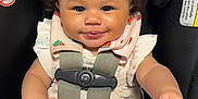 Milaya joined the competition — help win amazing prizes! baby, child, car_seat, curly_hair, smile, toy, seatbelt, clothing, infant, cute, sitting, safety, indoor, person, young_child, expression, playful, head, face, hands