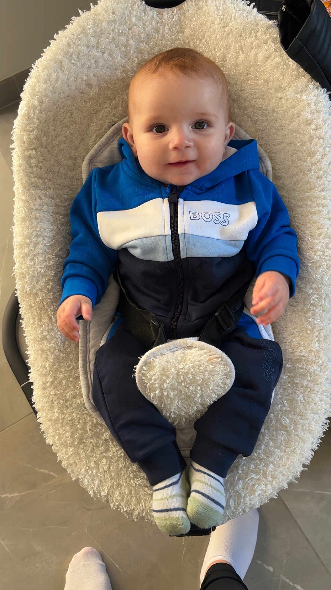 Isaac a rejoint le concours — aidez-le/la à gagner de superbes lots ! baby, child, blue_hoodie, bouncer_seat, cushion, floor, footwear, happy, indoor, infant, person, portrait, sitting, smile, sock, toddler, white_socks, young_child, zipper, casual_clothing