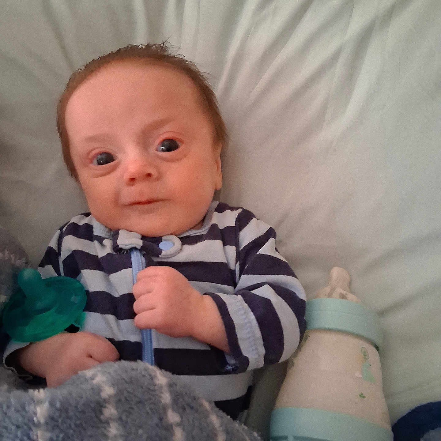 David Leo is registered to the contest to win money with this photo: baby, bed, blanket, bottle, comfort, cute, face, hand, indoors, infant, lying_down, newborn, pacifier, pillow, portrait, sleepwear, soft_texture, striped_clothing, wide_eyes, young_child