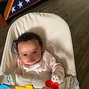 Amiylah joined the competition — help win amazing prizes! baby, infant, baby_seat, toy, mittens, curly_hair, pink_clothing, wooden_floor, flag_display, american_flag, triangular_flag_case, indoor, child, person, cushion, smiling, cute, young_child, home, playtime