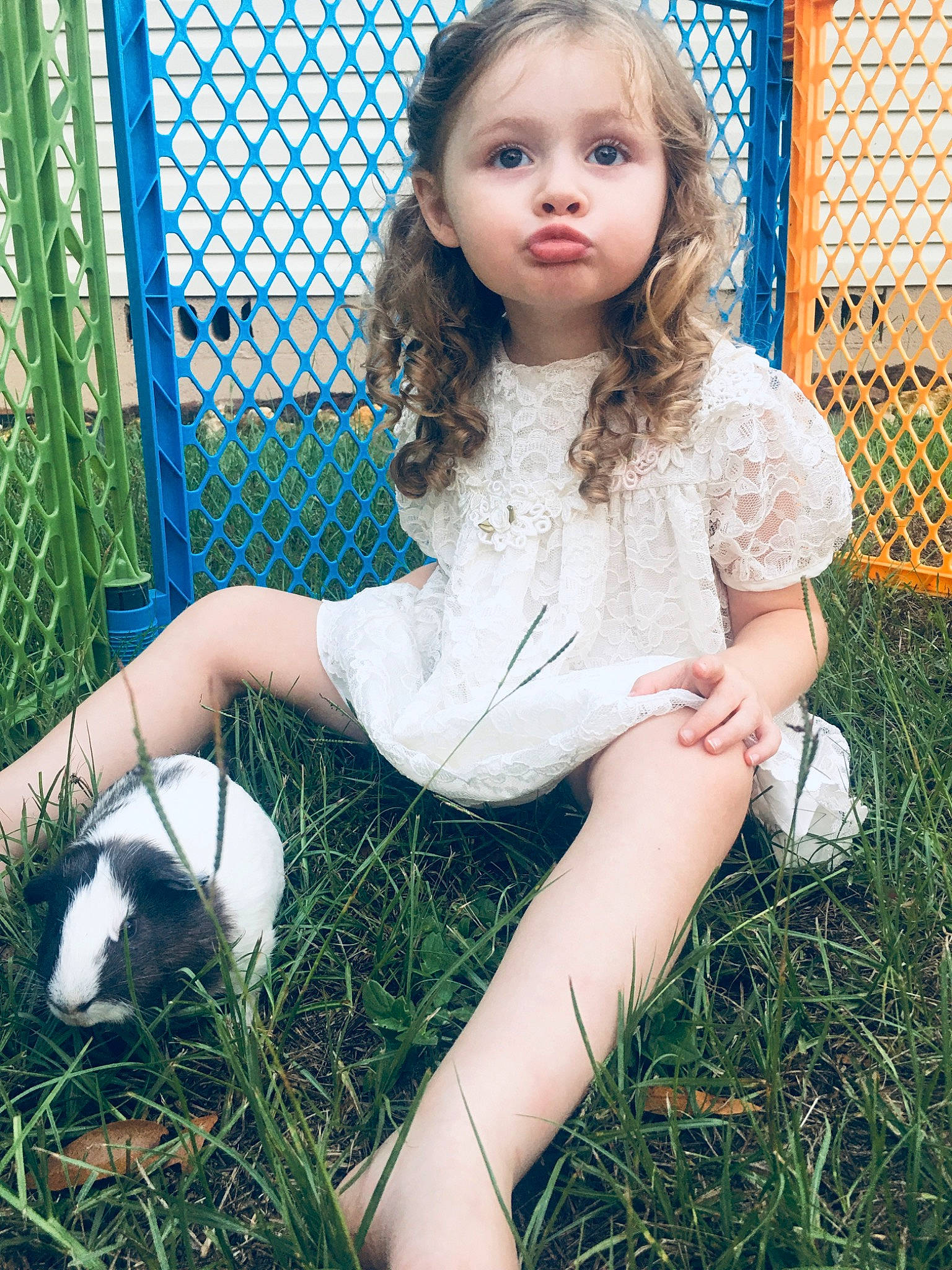 Rebecca joined the competition — help win amazing prizes! baby_toddler_clothing, chain_link_fencing, child_model, curtain, fence, foot, grass, mesh, net, person, shoe, sitting, wire_fencing