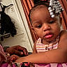 toddler, child, face, beads, braids, hair, hand, fabric, pattern, curtain, indoor, person, clothing, skin, portrait, closeup, expression, support, home, colorful