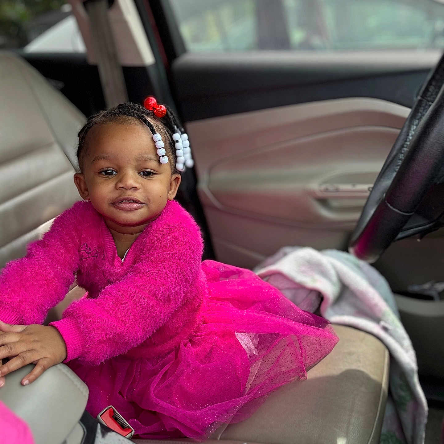 Brenlee is registered to the contest to win money with this photo: toddler, child, car, seat, pink_clothing, tulle_skirt, hair_beads, smile, interior, seatbelt, door, window, steering_wheel, bottle, blanket, person, portrait, cute, indoors, fashion