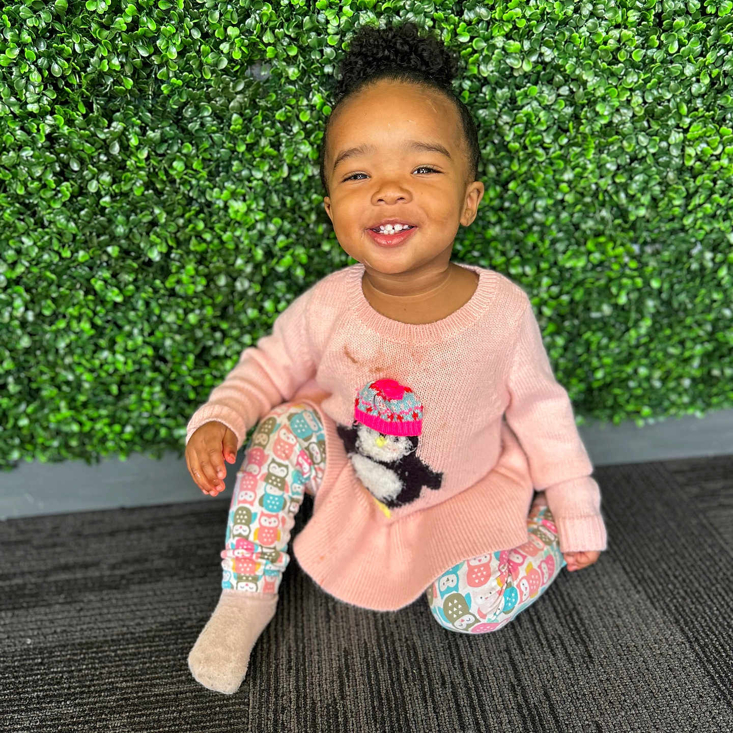Sapphyre is registered to the contest to win money with this photo: bright, carpet, child, colorful_leggings, curly_hair, cute, green_wall, happy, indoor, leafy_background, owl_pattern, penguin_design, pink_sweater, playful, portrait, sitting, smiling, sock, toddler, young_child