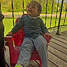 child, toddler, boy, sitting, red_chair, denim_shirt, bow_tie, gray_pants, green_socks, outdoor, deck, wooden_floor, porch, railing, spring, trees, grass, road, portrait, happy