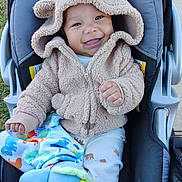 Sylas is registered to the contest to win money with this photo: baby, blanket, blue, child, cute, dinosaur_pattern, elephant_toy, face, grass, happy, hood, infant, jacket, outdoor, person, sidewalk, smiling, stroller, toy, warm_clothing