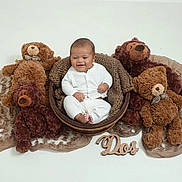 Elijah is registered to the contest to win money with this photo: baby, smiling, basket, plush_toy, teddy_bear, brown, white_clothing, soft_texture, cozy, infant, cute, child, indoor, portrait, sitting, fabric, decorative, happy, toy, wooden_sign