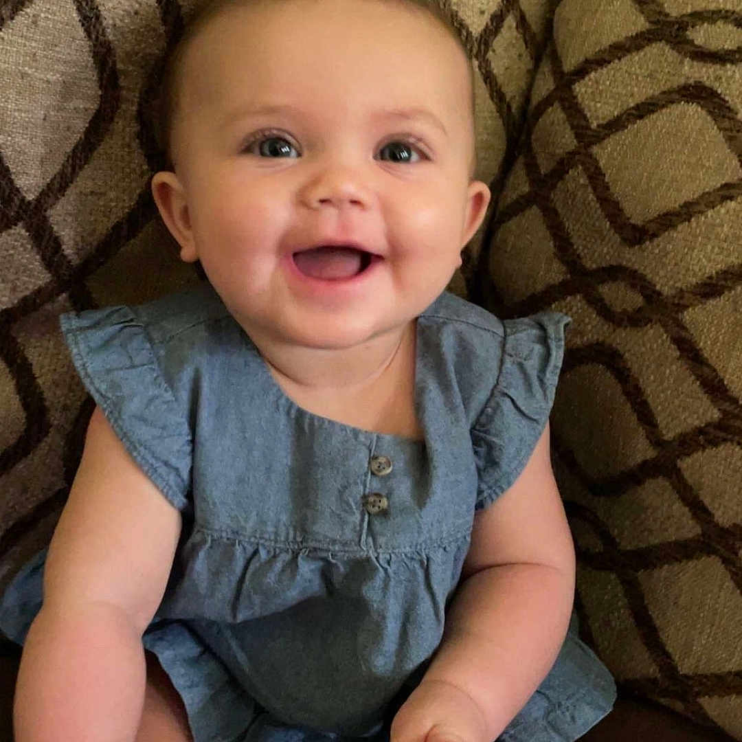 Anisliegh joined the competition — help win amazing prizes! baby, blue_dress, buttons, cheeks, child, couch, cute, eyes, face, footwear, happy, indoor, infant, patterned_cushion, short_hair, sitting, skin, small_hands, smiling, soft_lighting