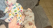 Ellie is registered to the contest to win money with this photo: dog, pajamas, stuffed_animal, bunny, blanket, chair, couch, tile_floor, indoor, pet, cute, relaxing, plush, pattern, fabric, ears, nose, animal_toy, cozy, home