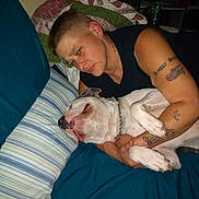 Barnabas joined the competition — help win amazing prizes! person, dog, bed, pillow, tattoo, indoor, sleeping, cuddling, pet, human, blanket, striped, chain_collar, comfort, affection, casual, short_hair, blue, resting, relaxation