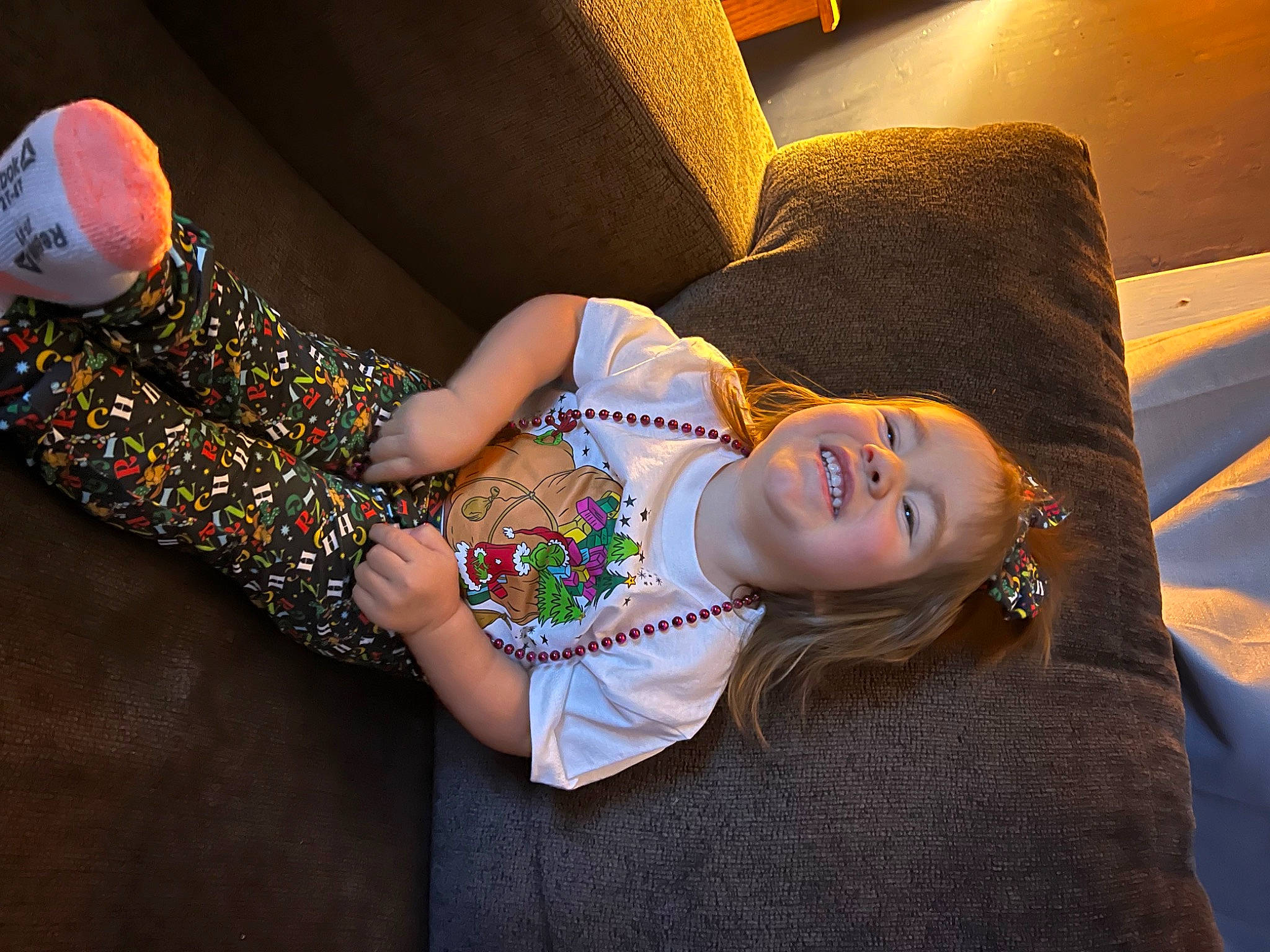 Addison is registered to the contest to win money with this photo: baby_toddler_clothing, child, comfort, couch, elbow, flash_photography, flooring, fun, happy, human_body, human_leg, joy, knee, leg, pattern, person, sitting, skin, smile, textile