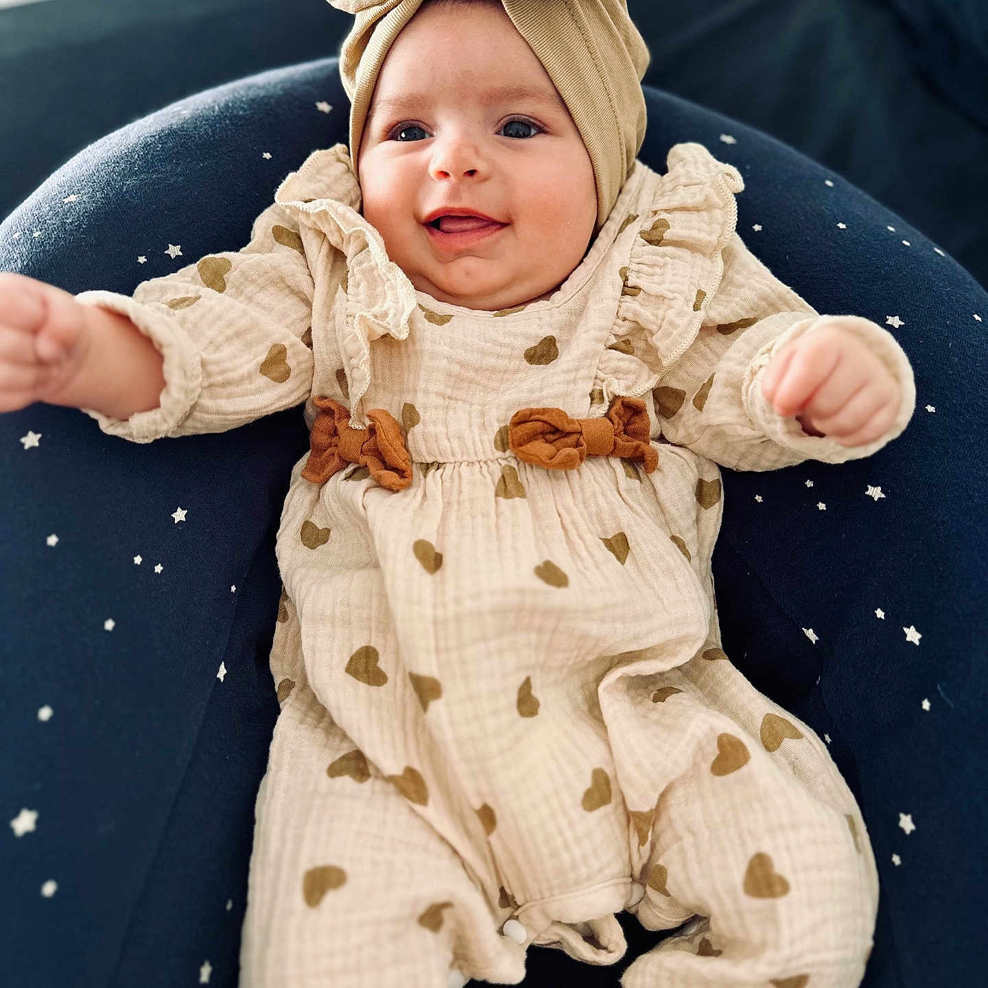 Livia a rejoint le concours — aidez-le/la à gagner de superbes lots ! baby, bow, child, clothing, cream_outfit, cushion, cute, footwear, happy, headband, hearts_pattern, indoors, infant, person, portrait, sitting, smiling, soft_lighting, star_pattern, young_child