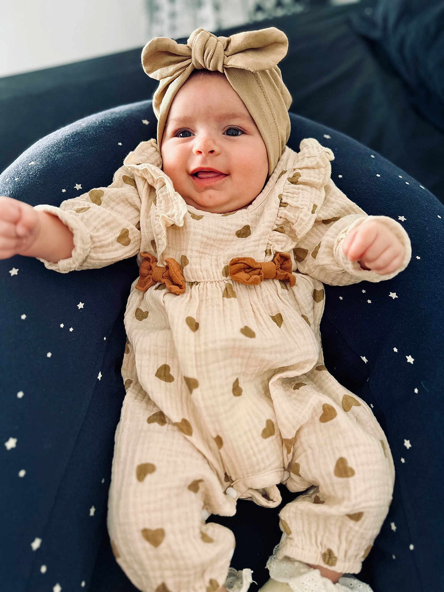 Livia a rejoint le concours — aidez-le/la à gagner de superbes lots ! baby, child, infant, smiling, headband, bow, cream_outfit, hearts_pattern, cushion, star_pattern, sitting, cute, happy, indoors, soft_lighting, portrait, clothing, footwear, person, young_child