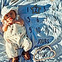baby, infant, milestone_blanket, white_clothing, hat, sandals, sunlight, shadow, numbers, months, baby_milestone, outdoor, portrait, cute, child, smile, fabric, pattern, soft_texture, lying_down