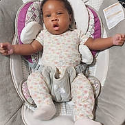 Skylar is registered to the contest to win money with this photo: baby, infant, onesie, baby_seat, cushion, patterned_clothing, arms_outstretched, curious_expression, indoor, soft_toys, plush, child, cute, comfort, small_person, face, smiling, resting, relaxed, home