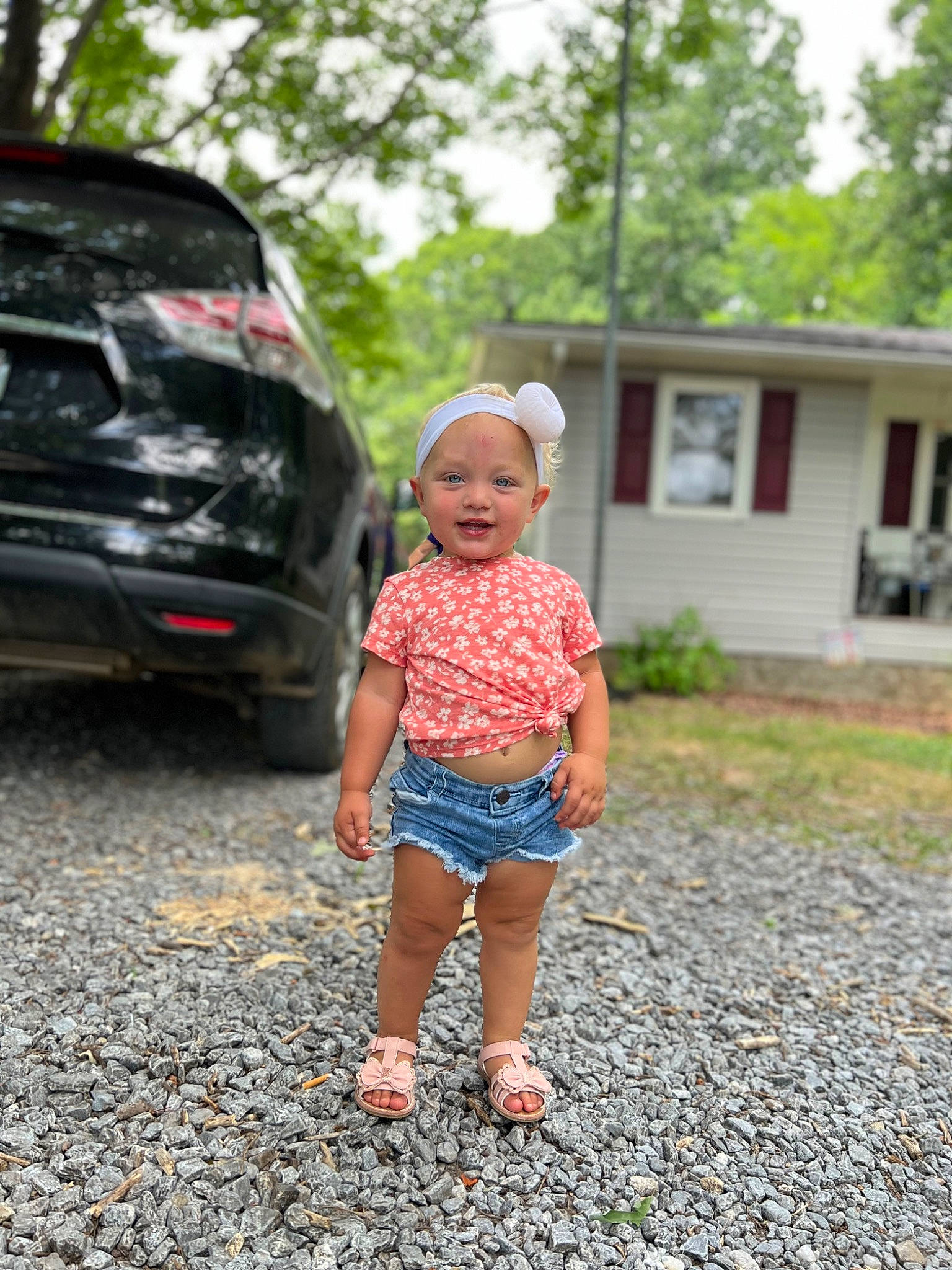 Emberlynn is registered to the contest to win money with this photo: asphalt, automotive_design, automotive_exterior, automotive_lighting, automotive_tire, bumper, car, grass, hat, headwear, house, joy, landscape, motor_vehicle, person, personal_luxury_car, plant, shorts, summer, toddler