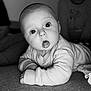 baby, child, infant, black_and_white, portrait, curious, tummy_time, indoors, wide_eyes, sweater, carpet, person, expression, candid, family, soft_light, young_child, face, background, observer
