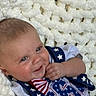 baby, smiling, infant, blanket, blue_eyes, clothing, stars, stripes, cute, portrait, face, child, happy, toddler, pattern, textile, hand, lying_down, soft, indoor