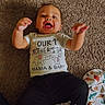 baby, child, smiling, carpet, clothing, tshirt, happy, indoor, infant, lying_down, person, blanket, animal_print, floor, cute, celebration, mother's_day, raised_hands, cheerful, casual